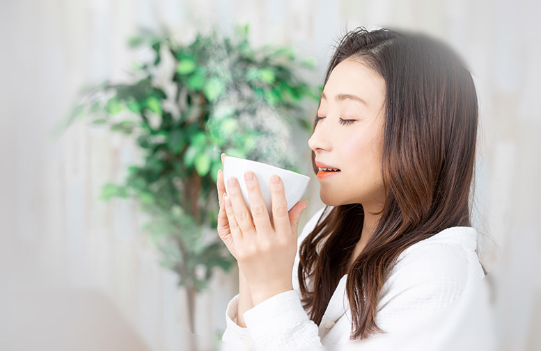 カップスープを飲む女性のイメージ画像