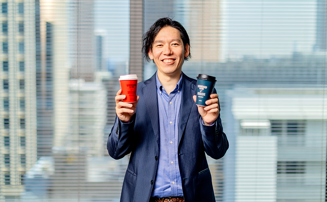 ファミマカフェを持って笑顔の高見沢さんの写真